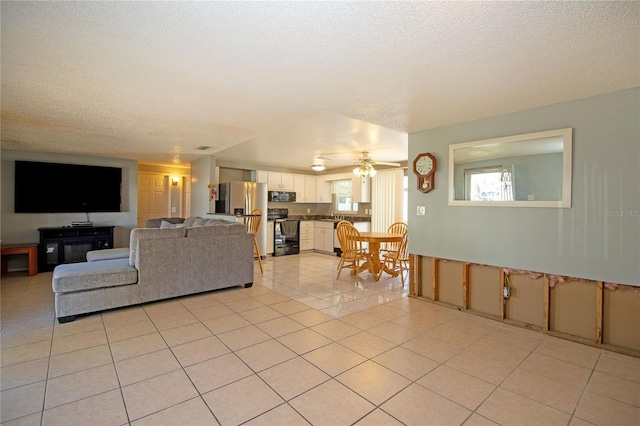 tiled living room with a textured ceiling and ceiling fan