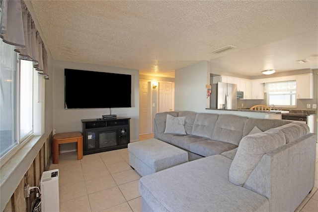 tiled living room featuring sink and a textured ceiling