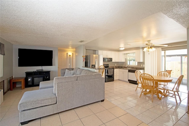 tiled living room with ceiling fan, sink, and a textured ceiling