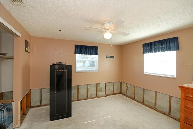 empty room with a textured ceiling and ceiling fan