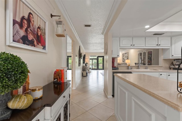 kitchen with light tile patterned floors, crown molding, white cabinetry, and a textured ceiling