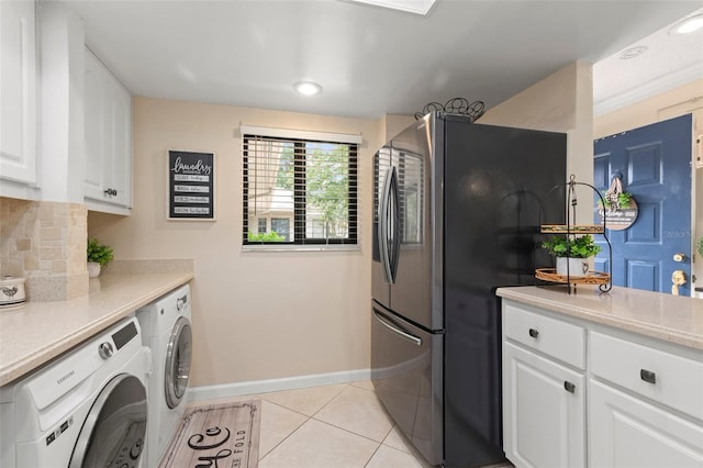 kitchen with light tile patterned floors, white cabinetry, stainless steel fridge, decorative backsplash, and washer and clothes dryer