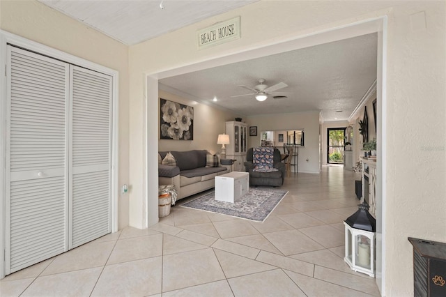 tiled living room with ornamental molding, a textured ceiling, and ceiling fan