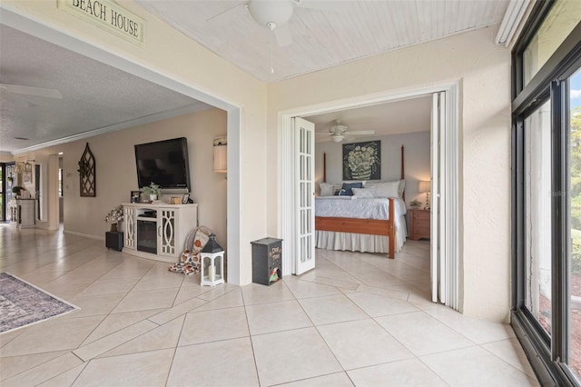 corridor with a textured ceiling, crown molding, and light tile patterned flooring