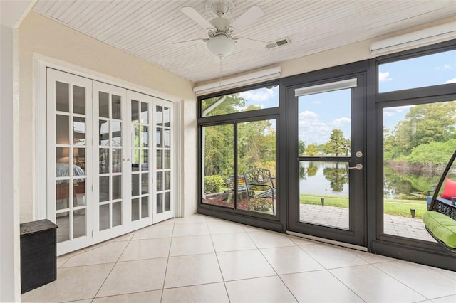 unfurnished sunroom featuring a water view, ceiling fan, and a healthy amount of sunlight