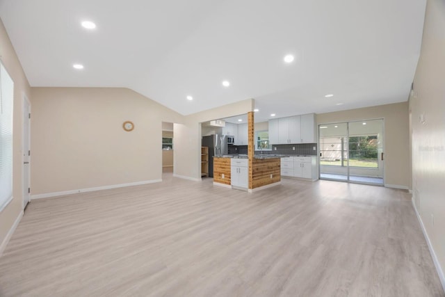 unfurnished living room featuring lofted ceiling and light wood-type flooring