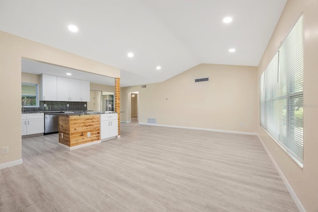 kitchen with vaulted ceiling, backsplash, stainless steel dishwasher, white cabinetry, and light wood-type flooring