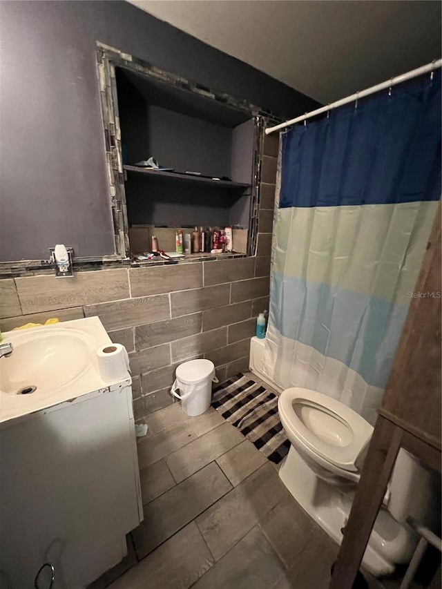 bathroom featuring tile walls, a shower with curtain, vanity, toilet, and tile patterned floors