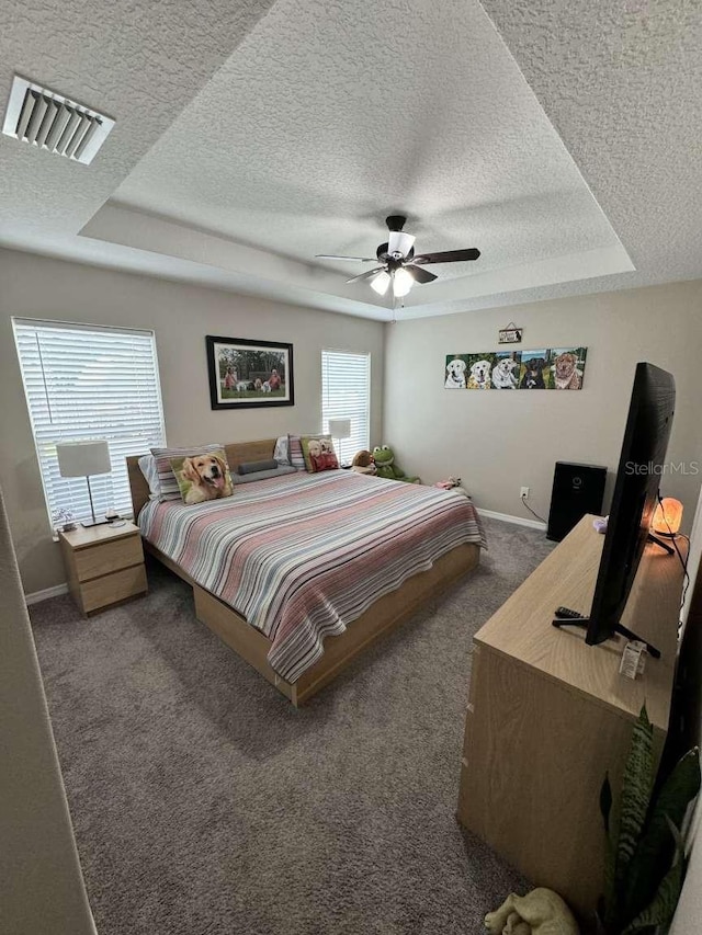 carpeted bedroom featuring a textured ceiling, a raised ceiling, and ceiling fan