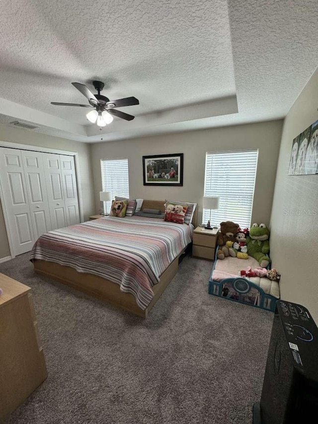 bedroom with ceiling fan, a closet, dark carpet, and multiple windows