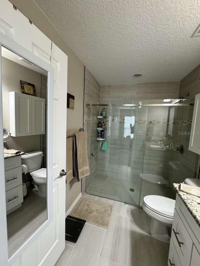 bathroom with a textured ceiling, vanity, toilet, and walk in shower