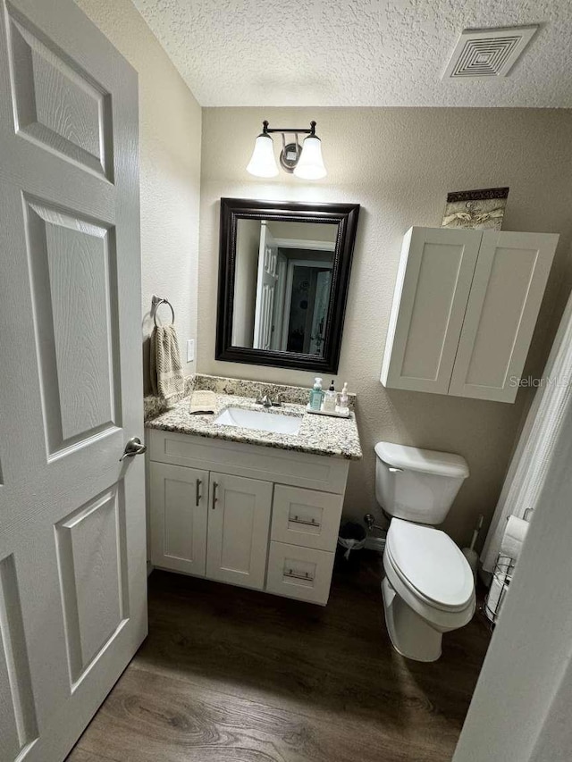 bathroom featuring hardwood / wood-style floors, vanity, a textured ceiling, and toilet