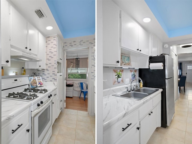 kitchen with white gas range oven, tasteful backsplash, sink, white cabinetry, and light tile patterned floors