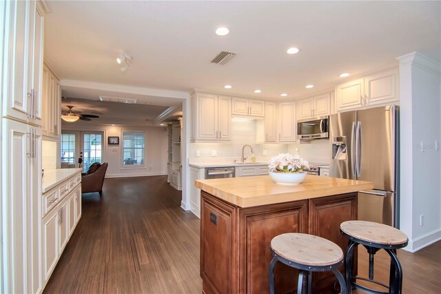 kitchen with dark hardwood / wood-style flooring, a center island, stainless steel appliances, white cabinetry, and ceiling fan