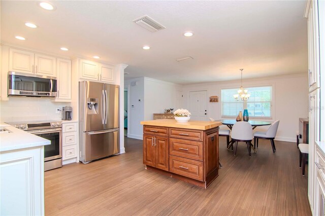 kitchen with a chandelier, light hardwood / wood-style flooring, decorative light fixtures, and stainless steel appliances