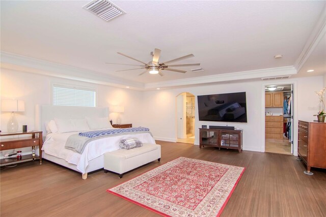 bedroom with ceiling fan, ensuite bath, a tray ceiling, and dark hardwood / wood-style flooring