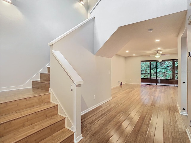 stairway featuring a baseboard radiator, hardwood / wood-style flooring, and ceiling fan