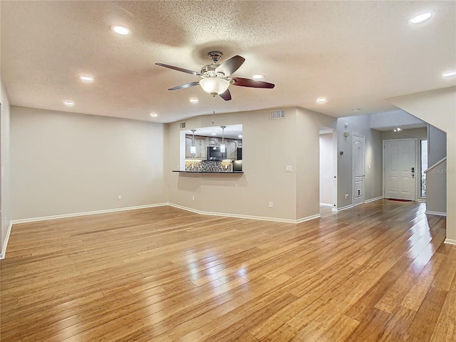 unfurnished living room featuring a textured ceiling, light wood-type flooring, and ceiling fan