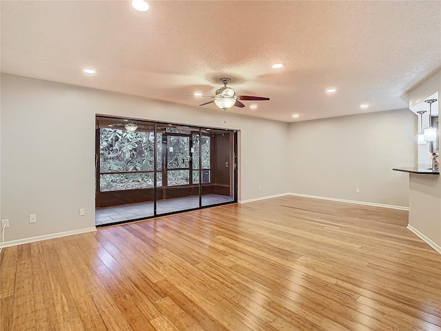 unfurnished living room featuring a textured ceiling, light wood-type flooring, and ceiling fan