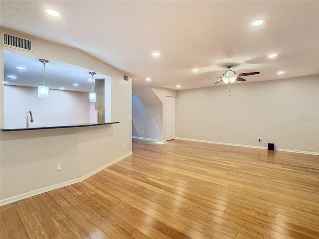 unfurnished living room featuring light hardwood / wood-style floors, a textured ceiling, and ceiling fan