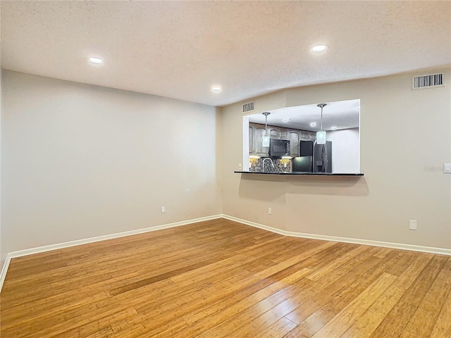 unfurnished living room with a textured ceiling and wood-type flooring