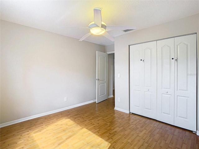 unfurnished bedroom with a closet, a textured ceiling, hardwood / wood-style flooring, and ceiling fan