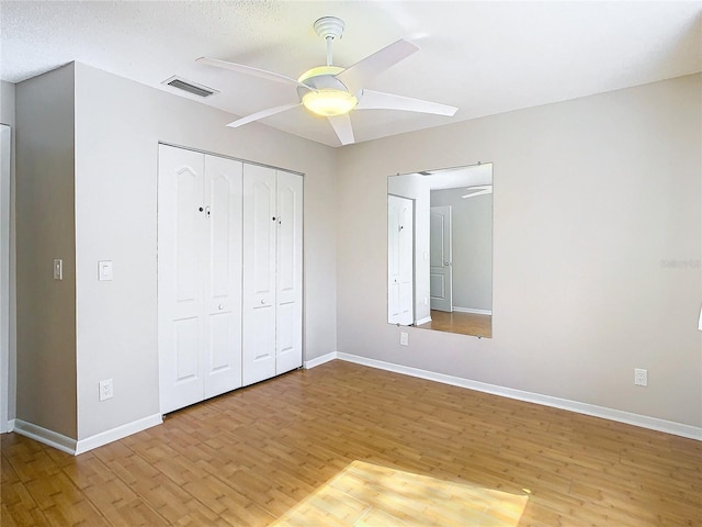 unfurnished bedroom featuring light hardwood / wood-style floors, a closet, a textured ceiling, and ceiling fan