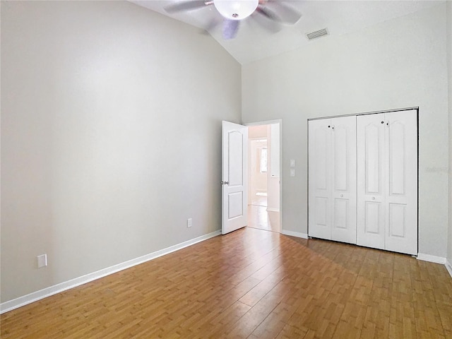 unfurnished bedroom with a closet, ceiling fan, wood-type flooring, and lofted ceiling