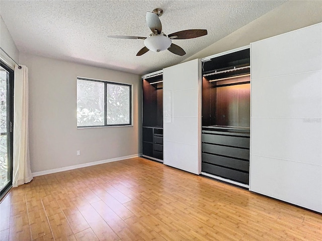 unfurnished bedroom featuring light hardwood / wood-style flooring, a textured ceiling, vaulted ceiling, and ceiling fan