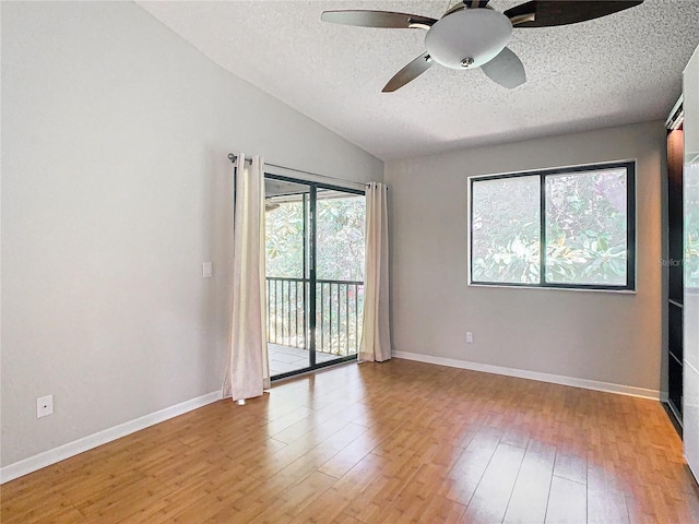 spare room with lofted ceiling, a textured ceiling, light wood-type flooring, and ceiling fan