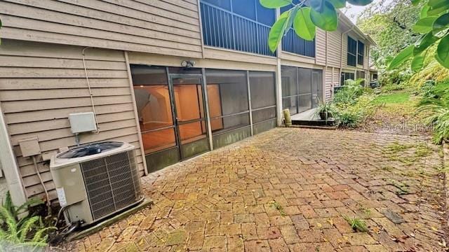 view of property exterior featuring central air condition unit, a patio area, and a sunroom