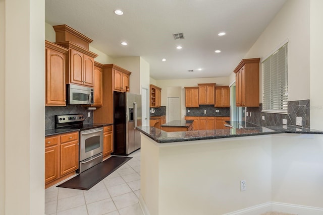 kitchen featuring decorative backsplash, stainless steel appliances, dark stone countertops, and kitchen peninsula