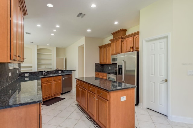 kitchen featuring tasteful backsplash, a kitchen island, light tile patterned floors, stainless steel appliances, and sink