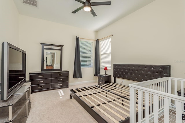 carpeted bedroom featuring ceiling fan and a crib