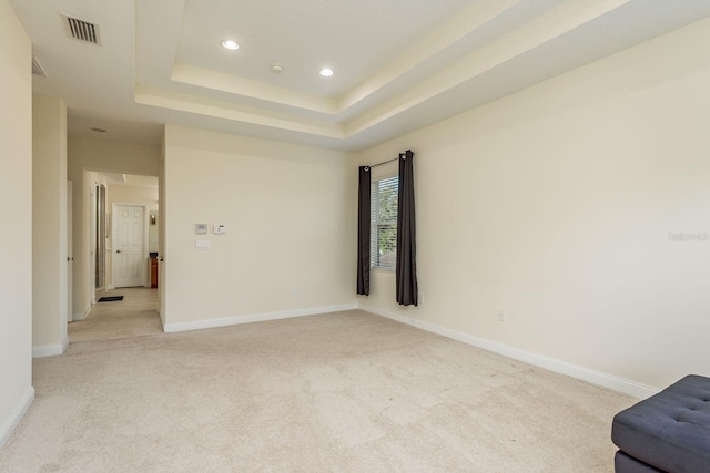 spare room featuring light carpet and a tray ceiling