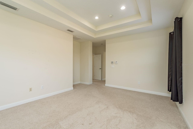 unfurnished room featuring a tray ceiling and light colored carpet