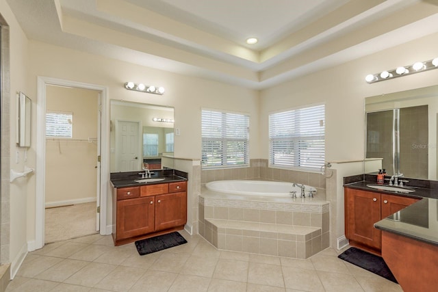 bathroom with tile patterned floors, a tray ceiling, vanity, and separate shower and tub