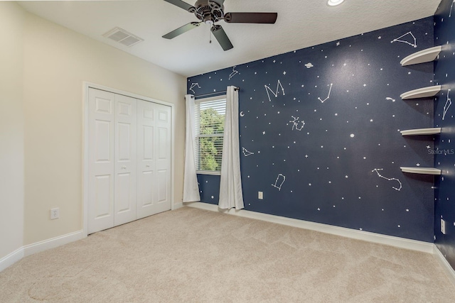 unfurnished bedroom featuring ceiling fan, a textured ceiling, a closet, and carpet flooring