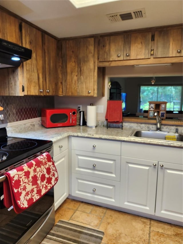 kitchen featuring stainless steel electric range oven, sink, white cabinets, and exhaust hood