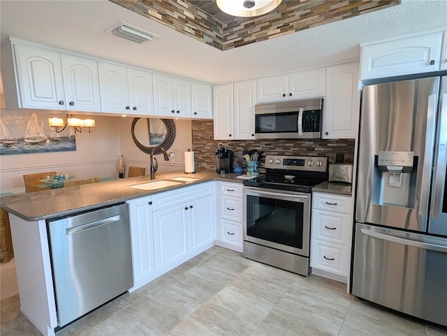 kitchen with dark stone countertops, white cabinetry, sink, and appliances with stainless steel finishes