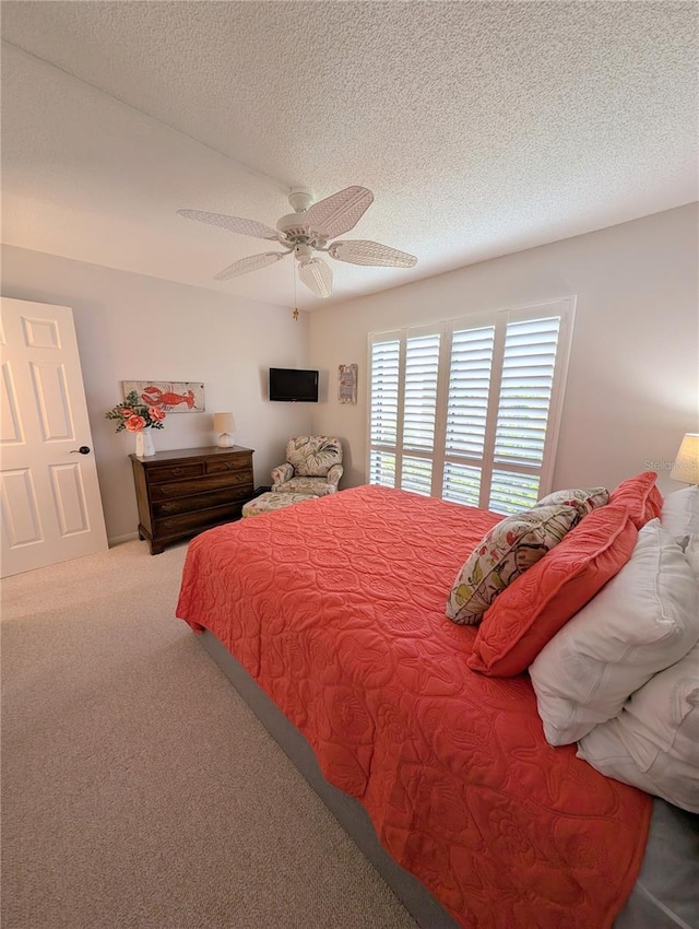 carpeted bedroom featuring ceiling fan and a textured ceiling