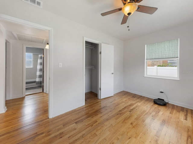 unfurnished bedroom featuring ceiling fan, a closet, a walk in closet, and light hardwood / wood-style flooring