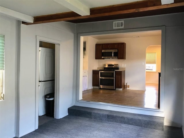 corridor featuring beamed ceiling and stacked washer and dryer