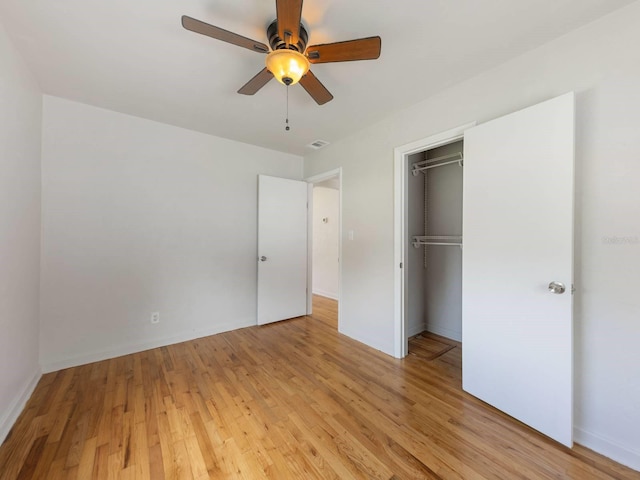 unfurnished bedroom with a closet, light hardwood / wood-style floors, a spacious closet, and ceiling fan