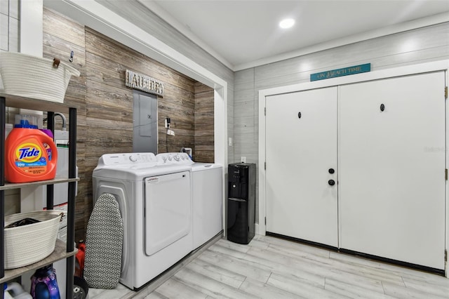 clothes washing area with wooden walls, light hardwood / wood-style floors, and washer and dryer