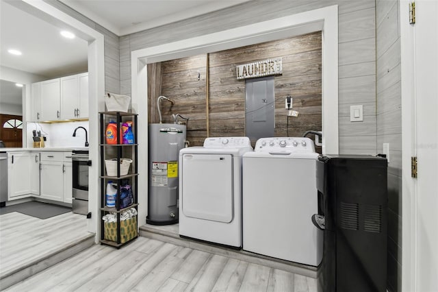 washroom with light wood-type flooring, independent washer and dryer, electric water heater, and cabinets