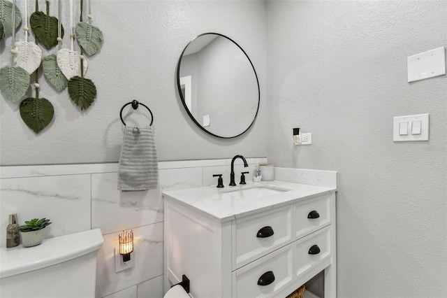 bathroom featuring vanity, tile walls, and toilet