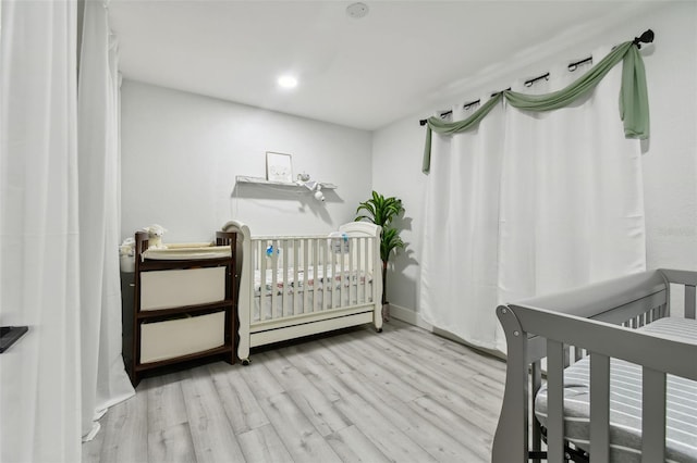 bedroom featuring a crib and light hardwood / wood-style flooring