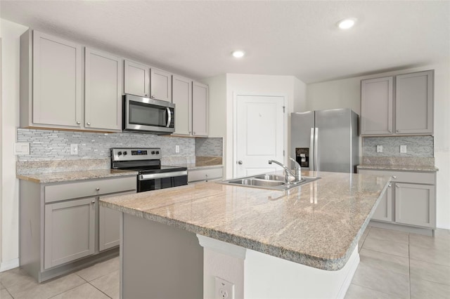 kitchen with gray cabinets, stainless steel appliances, an island with sink, and sink