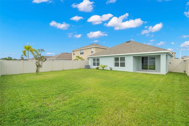 rear view of house with a yard, a patio, and central AC